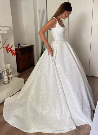 Sparkling ball gown wedding dress with a square neckline and thick straps, crafted from shimmering fabric, offering a classic yet glamorous bridal look.