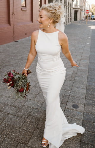 Sophisticated sleeveless bridal dress in ivory featuring a sleek fitted design, high neckline, and a timeless train, ideal for contemporary weddings