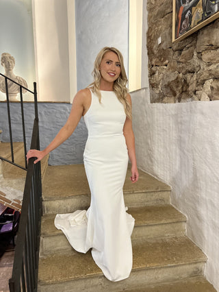 Chic ivory gown with a bateau neckline, curve-hugging silhouette, and flowing floor-length train, tailored for understated and modern bridal aesthetics