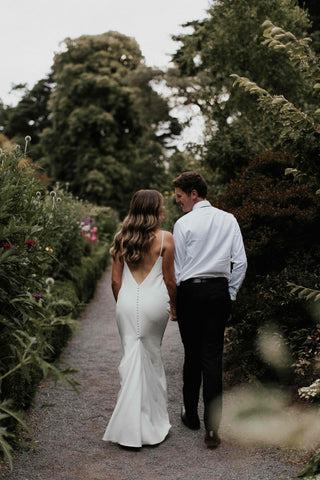 Romantic ivory sleeveless bridal gown with a modern high neckline, sleek fitted silhouette, and dramatic train, designed for stylish and timeless weddings