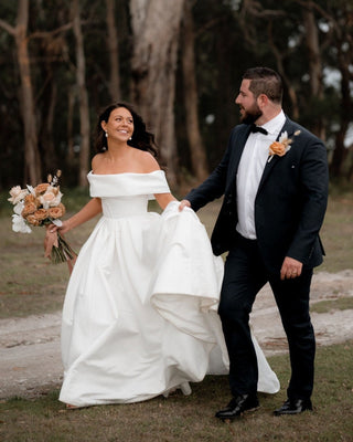 Sophisticated A-line wedding gown with a voluminous train, off-the-shoulder sleeves, and romantic design for unforgettable wedding moments.