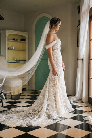 Chic ivory bridal gown with floral lace applique, sheer off-the-shoulder puff sleeves, sweetheart neckline, and dramatic fit-and-flare silhouette, tailored for modern fairy-tale weddings