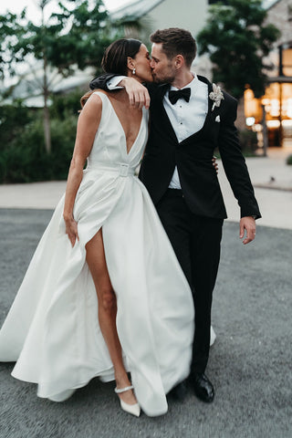 Romantic ivory A-line bridal gown adorned with satin fabric, deep V-neckline, and a high slit, perfect for glamorous outdoor wedding ceremonies