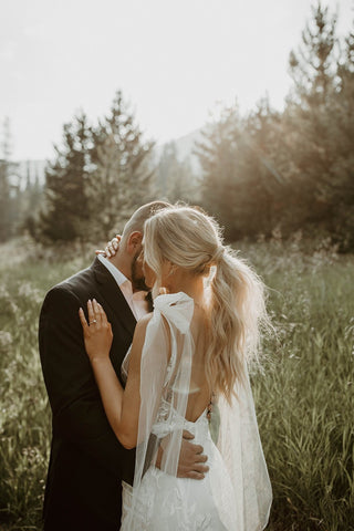 Chic lace bridal dress featuring a sheer floral overlay, a deep V-neckline, and a sleek fitted silhouette with a subtle train, ideal for contemporary weddings