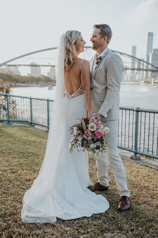 Elegant white bridal gown with a stunning low-back design and intricate lace detailing, perfect for a modern outdoor wedding