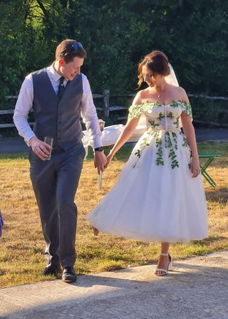 Elegant ivory wedding dress featuring intricate floral lace applique, sweetheart neckline, off-the-shoulder puff sleeves, and a tea-length A-line design, ideal for timeless bridal looks