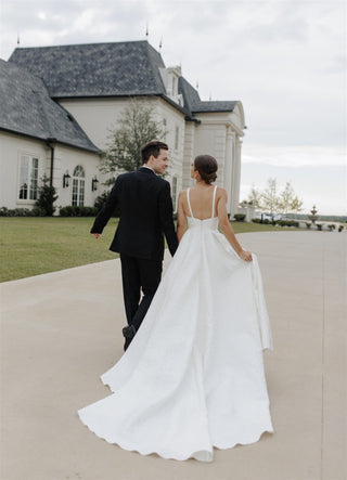 Sophisticated ivory A-line bridal gown with a plunging neckline, sleeveless bodice, and flowing skirt, designed for minimalist and timeless wedding aesthetics