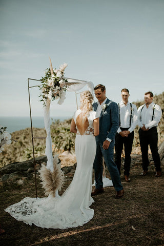 Chic ivory high-low wedding dress with cap sleeves and a minimalist design, tailored for modern and understated bridal looks in outdoor settings