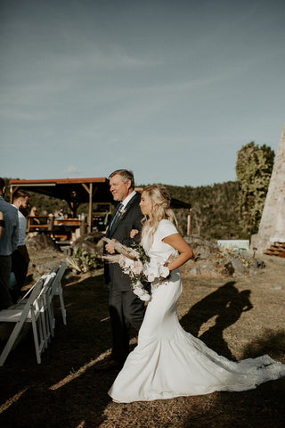 Sophisticated high-low ivory wedding dress featuring cap sleeves and a flowing hemline, designed for effortless elegance in casual and outdoor wedding settings