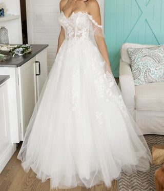 Romantic off-the-shoulder bridal gown with a lace bodice and a voluminous tulle skirt, perfect for a dreamy wedding