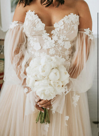 Romantic ivory ball gown with floral lace embroidery, strapless deep V-plunge neckline, A-line tulle design, and detachable puff sleeves, tailored for a magical fairytale wedding