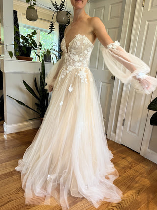 Custom ivory bridal gown with 3D floral lace applique, strapless deep V-neckline, A-line tulle silhouette, and detachable sheer puff sleeves, perfect for a princess fairytale wedding