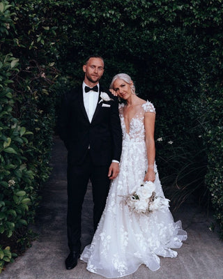 Chic backless ivory ball gown with floral applique, deep V-plunge neckline, cap sleeves, and tulle A-line silhouette, tailored for whimsical princess weddings