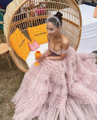 Ethereal pastel pink gown with delicate ruffled layers, a lace-up corset back, and an off-the-shoulder neckline, designed for brides or special occasions with a touch of glamour