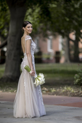 Classic bridal look with a fitted lace gown featuring illusion details and floral accents, paired with a groom in a formal white dinner jacket, perfect for luxurious outdoor wedding venues