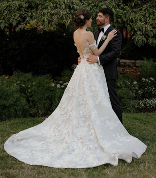 Sophisticated custom ivory bridal dress with sparkly sequin detailing, floral lace applique, off-the-shoulder puff sleeves, and a sweetheart neckline, designed for magical princess weddings