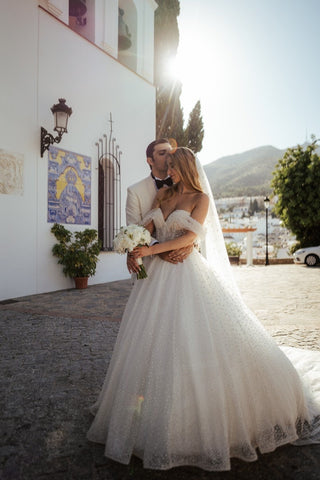 A long, flowing veil enhances the elegance of the ensemble, perfect for traditional or garden weddings