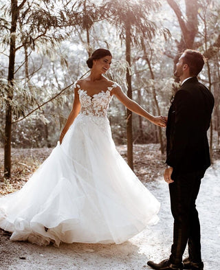 Ethereal bridal gown with an illusion lace bodice, intricate floral motifs, and a voluminous tulle skirt, ideal for romantic weddings or garden ceremonies