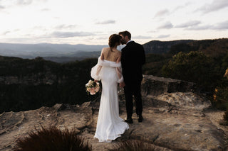 Sophisticated wedding dress with sheer billowing sleeves, a figure-hugging fit, and a clean design, creating a romantic yet contemporary look for garden ceremonies