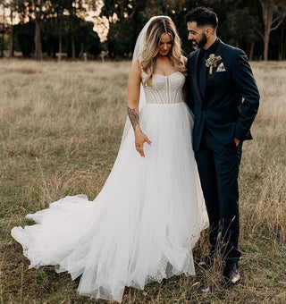 Elegant ivory bridal gown featuring a structured corset top, dotted tulle skirt, and a romantic A-line silhouette, ideal for rustic and whimsical wedding themes