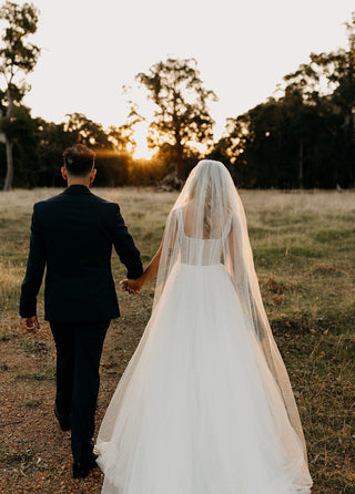 Romantic ivory corset wedding gown adorned with polka dot tulle and a soft A-line silhouette, complemented by a sheer veil, perfect for outdoor or woodland weddings