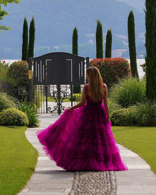 Elegant magenta tulle gown featuring cascading ruffles, a fitted corset-style bodice, and delicate spaghetti straps, ideal for modern proms or formal celebrations