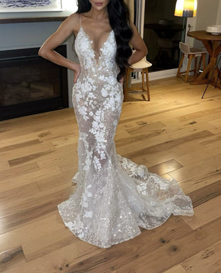 Stunning mermaid wedding gown with a plunging illusion neckline, intricate floral lace appliqués, and shimmering sequin detailing, complemented by a dramatic chapel train, perfect for glamorous and elegant ceremonies