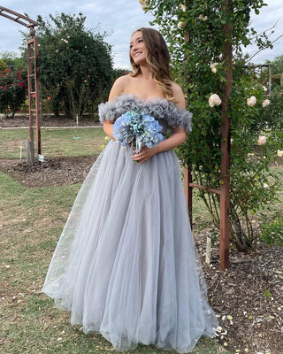 Romantic ivory tulle ball gown adorned with floral lace applique, off-the-shoulder neckline, and a flowing floor-length design, perfect for fairy-tale-inspired wedding ceremonies