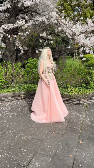 Elegant peach-coloured dress featuring embroidered floral details, a corset-style bodice, and a voluminous tulle skirt, ideal for romantic outdoor events and nature-themed occasions