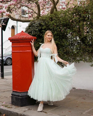 Soft pastel green tulle dress with delicate polka dot details, corset-style bodice, and adjustable ribbon straps, complemented by a tiered midi-length skirt, perfect for spring garden parties or whimsical outdoor events