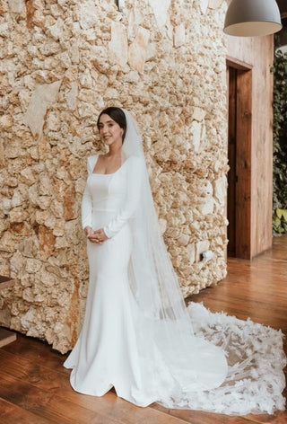 Elegant long-sleeve ivory wedding gown with a square neckline, fitted silhouette, and a dramatic floral lace train, perfect for timeless and sophisticated bridal celebrations