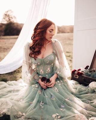 Sophisticated sage green tea-length dress adorned with floral embroidery, a structured bodice, and sheer sleeves, designed for enchanting outdoor gatherings and modern bridal looks