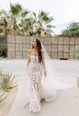 Elegant ivory wedding dress featuring intricate floral embroidery, sweetheart neckline, thin decorated straps, and dramatic mermaid fit-and-flare design, ideal for glamorous bridal occasions