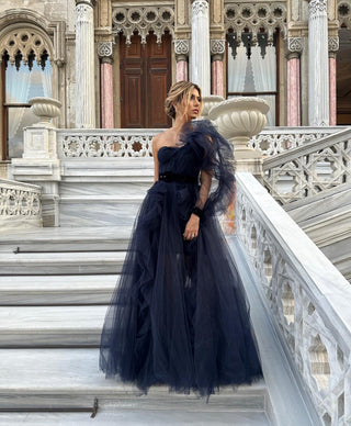 Elegant dark blue ball gown featuring cascading tulle layers and a statement shoulder detail, perfect for evening glamour