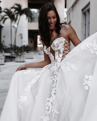 Ethereal wedding dress showcasing a sheer lace bodice with botanical motifs and a flowing voluminous skirt, ideal for a modern bride.