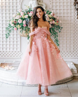 Dreamy blush pink dress featuring a strapless sweetheart neckline, delicate floral appliqués, and a layered tulle midi skirt, perfect for romantic weddings or garden parties