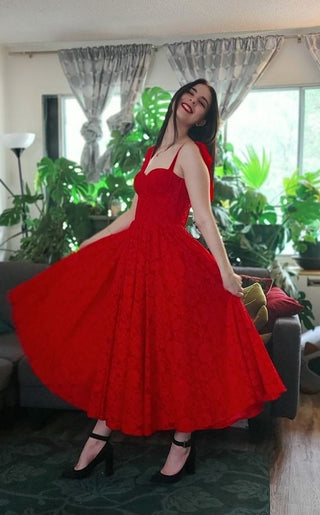 A striking red midi dress with intricate lace detailing and a structured corset bodice, featuring adjustable shoulder ties for an elegant and timeless formal look