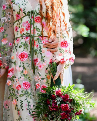 Romantic cream and beige ball gown, adorned with multicoloured floral embroidery, long puff sleeves, and an A-line floor-length style, tailored for bohemian and fairycore-themed events