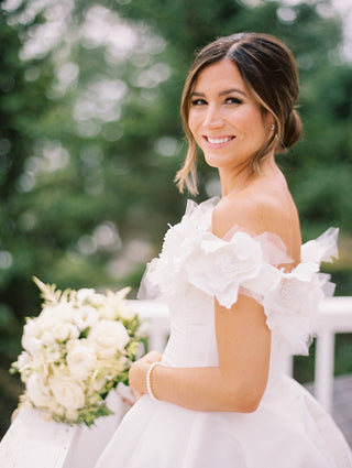 Stunning ivory wedding dress with a classic off-the-shoulder style, floral accents, and a sweeping A-line skirt for a fairy-tale aesthetic