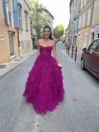 Vibrant fuchsia ball gown with tiered ruffled tulle layers, a structured bodice, and thin straps, perfect for glamorous evening events and special occasions