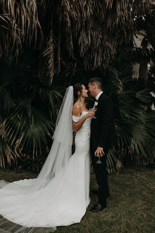 Chic off-shoulder wedding gown with a soft draped bodice and floor-length train, ideal for a sophisticated bride