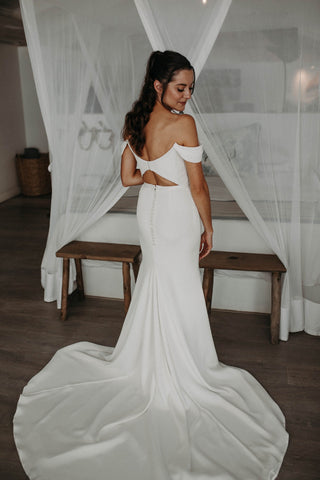 Timeless white wedding dress with off-shoulder neckline and classic silhouette, creating an effortless bridal style