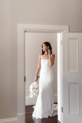 Elegant ivory wedding dress featuring sequin-embroidered patterns, a low-back design, and a graceful A-line fit, ideal for sophisticated and timeless bridal occasions