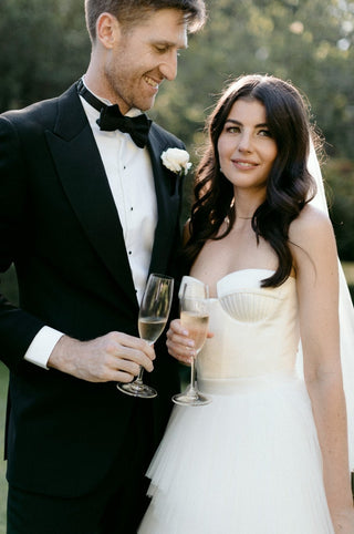 Classic white bridal gown with structured detailing, a flowing tulle skirt, and a romantic veil for an unforgettable wedding day look.