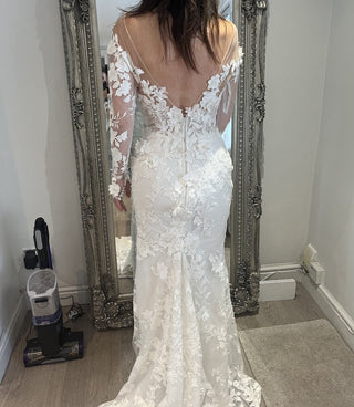 Romantic ivory fit-and-flare bridal gown, adorned with floral lace applique, deep V-neckline, sheer puff off-the-shoulder sleeves, and mermaid silhouette, perfect for an elegant and timeless wedding