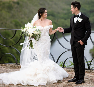 Ivory bridal gown featuring floral embroidery, off-the-shoulder neckline, form-fitting mermaid silhouette, and shimmering details, ideal for timeless and sophisticated weddings