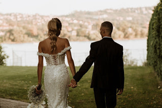 Romantic ivory bridal gown adorned with delicate lace applique, sparkling embellishments, off-the-shoulder neckline, and a dramatic fit-and-flare mermaid design, perfect for glamorous wedding celebrations