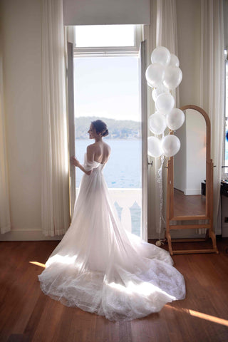 Modern fairytale bridal look with a glittering tulle gown, corset-style top, and sheer off-shoulder straps, paired with a soft, billowing veil