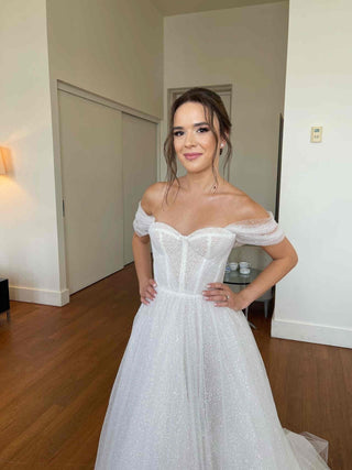 Dreamy tulle wedding gown with beaded corset bodice, off-the-shoulder straps, and long flowing veil, captured in a dramatic industrial setting