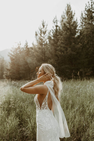 Romantic ivory wedding dress adorned with intricate floral lace, a plunging neckline, and a figure-hugging design, perfect for stylish and modern ceremonies